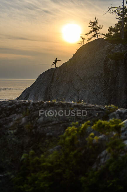 Silhouette of man standing on one leg on cliff, Ontario, Canada — Stock Photo