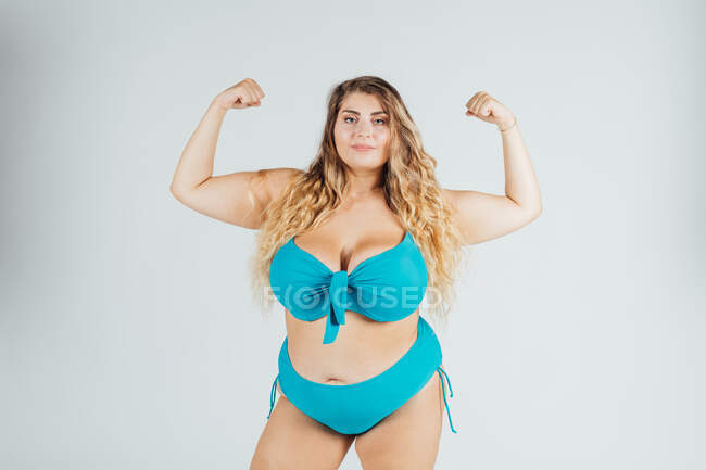 Jeune femme en bikini, muscles fléchissants — Photo de stock