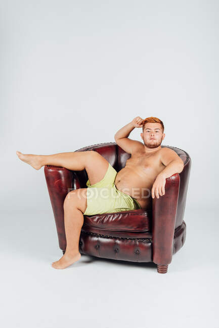 Portrait de jeune homme confiant dans un fauteuil avec la jambe levée — Photo de stock