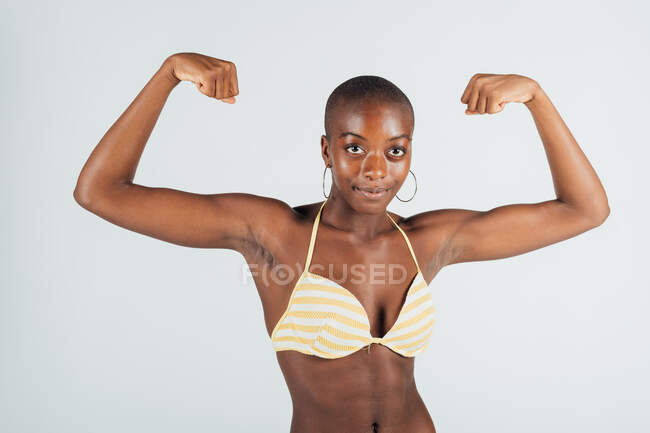 Junge Frau trägt Bikini, lässt Muskeln spielen — Stockfoto