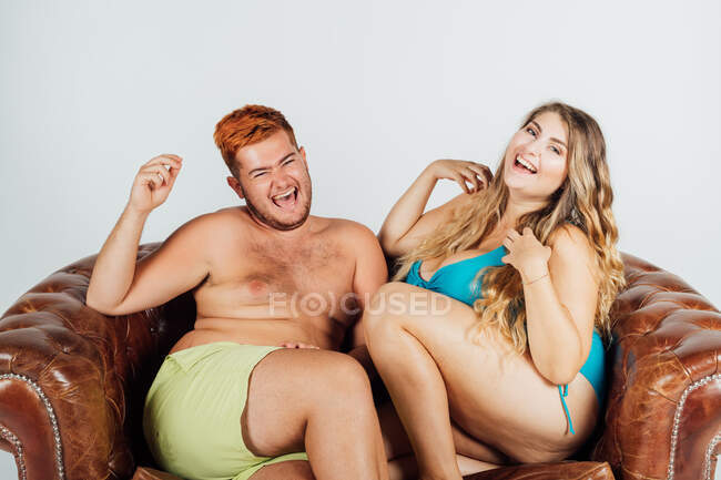 Jovem e mulher rindo, no sofá, parcialmente vestido — Fotografia de Stock