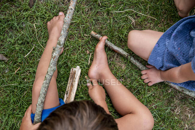 Cropped view of children with sticks — Stock Photo