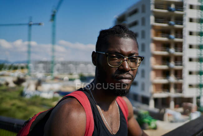 Young man wearing glasses, buildings in background — Stock Photo