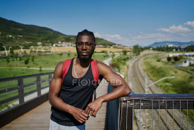 Молодой человек на мосту, смотрит в камеру — стоковое фото