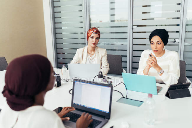 Three female colleagues working at shared desk — Stock Photo