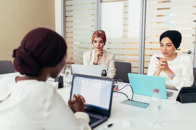 Three female colleagues working at shared desk — Stock Photo