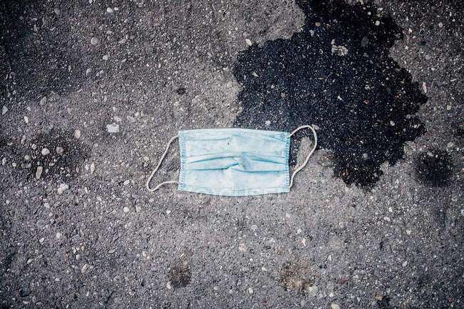 Discarded disposable face mask on sidewalk during 2020 Covid-19 — Stock Photo