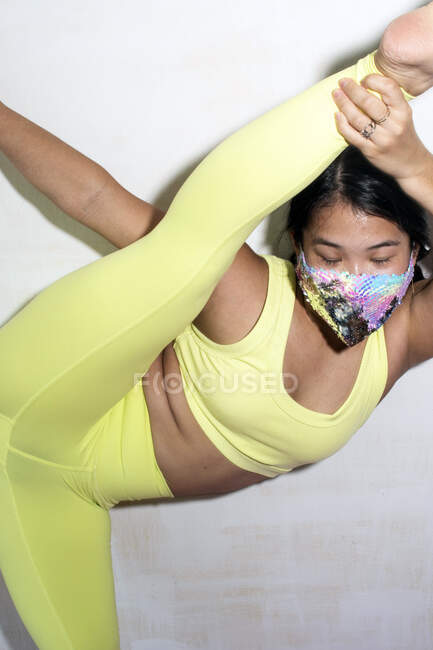 Contortionist holding leg, wearing face mask — Stock Photo