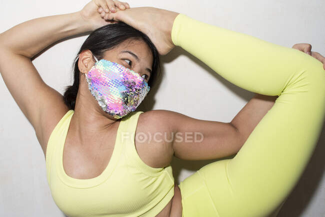 Contortionist with foot on head, wearing face mask — Stock Photo