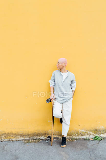Portrait of skateboarder in front of yellow wall — Stock Photo