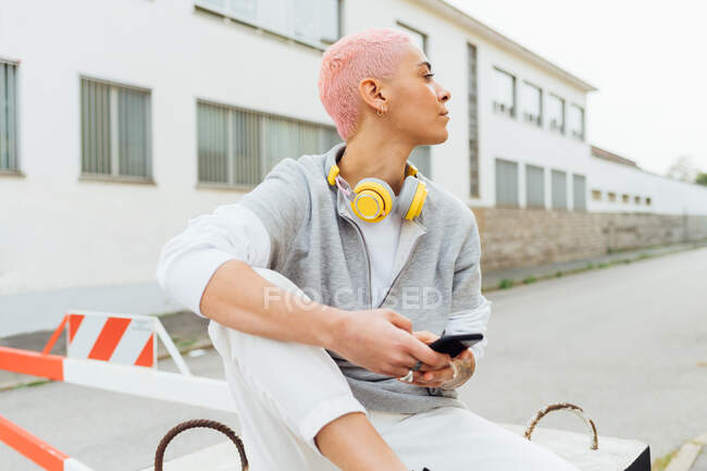Jovem mulher usando celular, olhando para longe — Fotografia de Stock