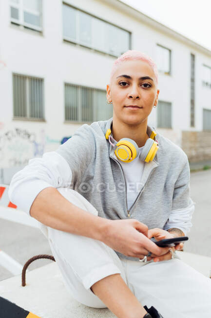 Retrato de mujer joven fuera de los edificios, usando el teléfono celular - foto de stock