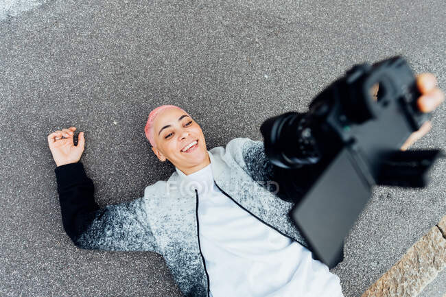 Фотограф лежит на земле и делает селфи с камерой — стоковое фото