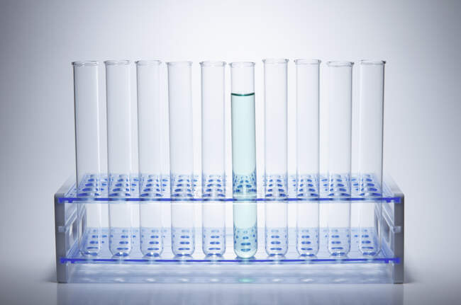 Test tubes in a rack, with one test tube containing green liquid — Stock Photo