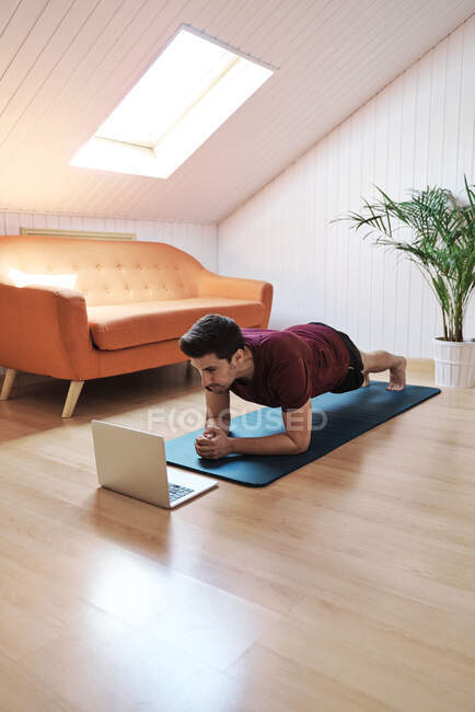 Hombre siguiendo la clase de ejercicio en el ordenador portátil - foto de stock