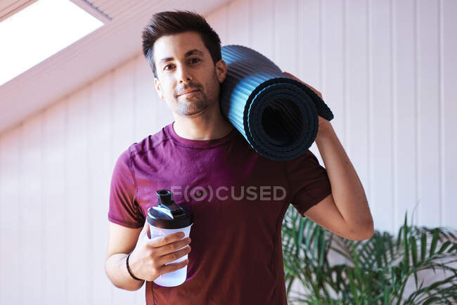 Man ready for exercise with mat and bottle — Stock Photo