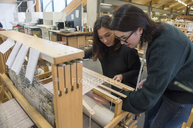 Estudiantes tejiendo con telar en taller textil - foto de stock