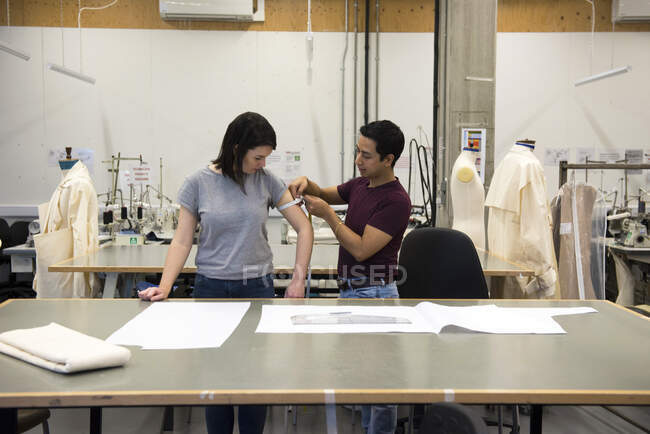 Студенты моды, мужчина измеряет женскую руку — стоковое фото