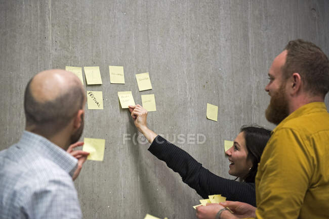 Students using sticky notes on wall to brainstorm ideas — Stock Photo