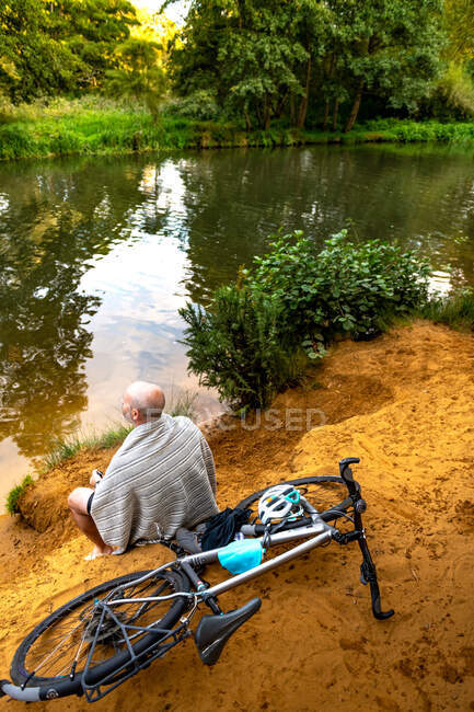 Пловец, сидящий у реки на велосипеде — стоковое фото