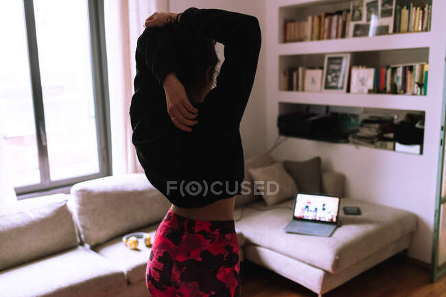 Woman stretching, following online exercise class — Stock Photo