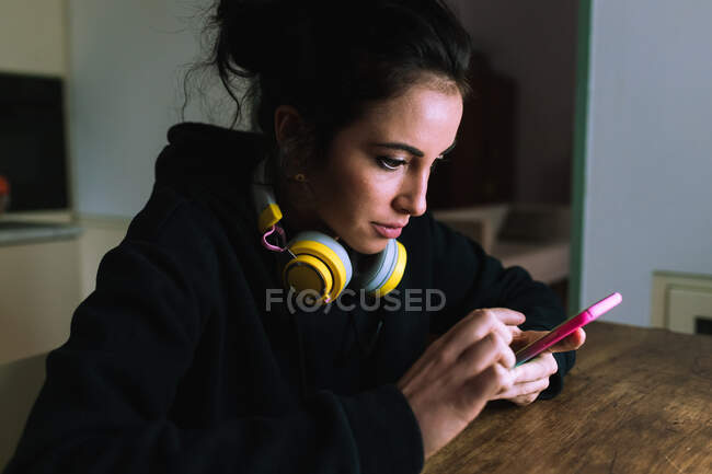 Mujer joven con auriculares, mirando su teléfono - foto de stock