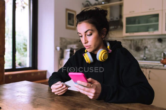 Young woman making credit card purchase on phone — Stock Photo
