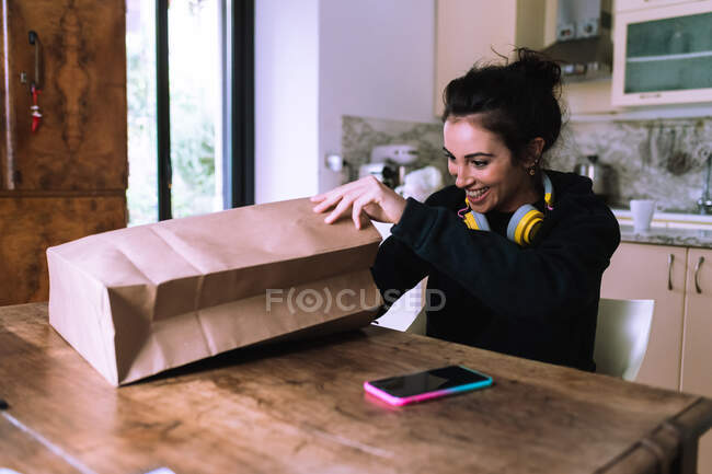 Mulher em casa, olhando dentro do saco de compras de papel — Fotografia de Stock