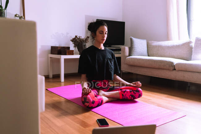 Молода жінка практикує йогу та медитацію вдома — стокове фото