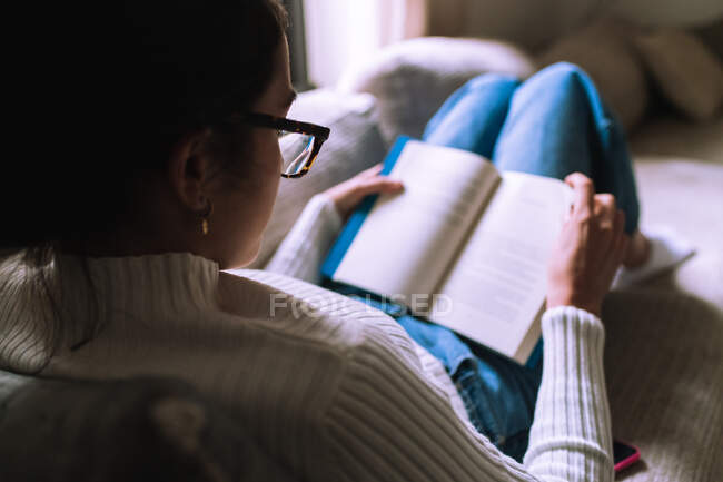 Jovem mulher lendo um livro em casa — Fotografia de Stock