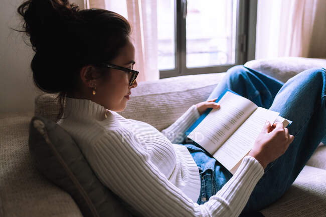 Giovane donna che legge un libro a casa — Foto stock