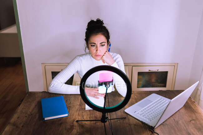 Young woman having video call, using ring light and phone — Stock Photo