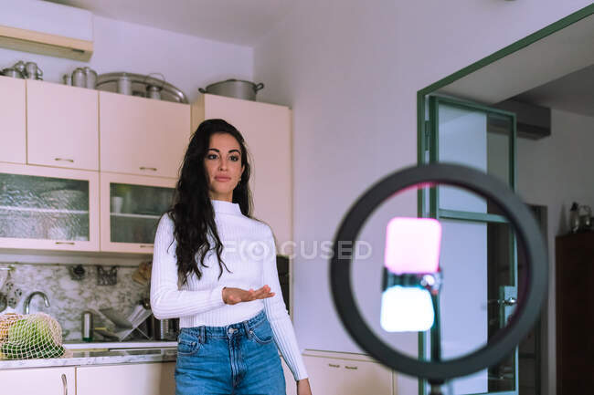 Young woman making video, using ring light and phone — Stock Photo
