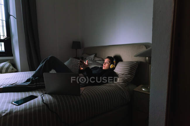 Молода жінка використовує мобільний телефон у ліжку — стокове фото