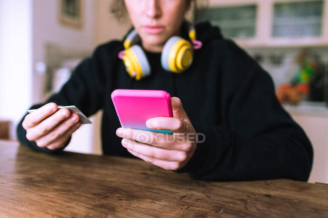 Young woman making a credit card purchase using mobile phone — Stock Photo