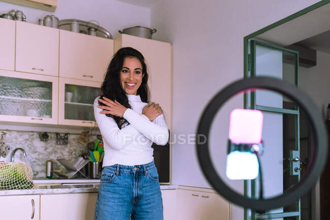 Young woman making a video at home, using mobile phone and ring — Stock Photo