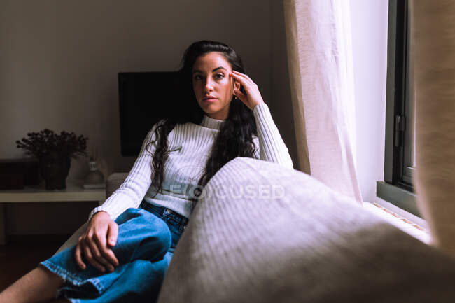 Ernsthafte junge Frau sitzt auf Sofa — Stockfoto