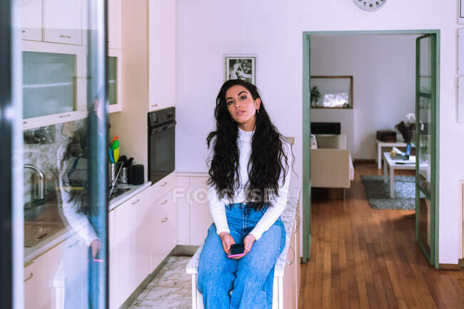 Jeune femme assise sur le comptoir de la cuisine — Photo de stock