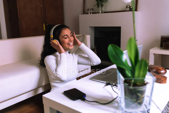 Jeune femme à la maison, écoutant de la musique sur ordinateur portable — Photo de stock