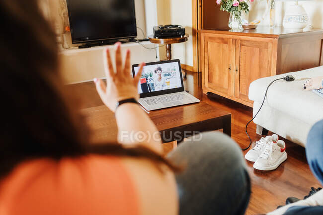 Женщина на видео-вызове с помощью ноутбука, машет — стоковое фото