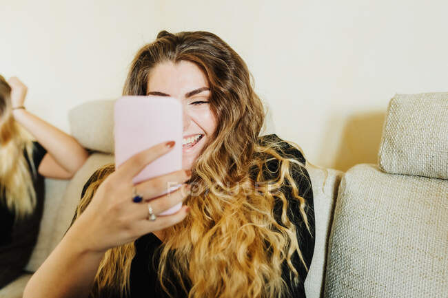 Молода жінка з телефоном, посміхаючись — стокове фото