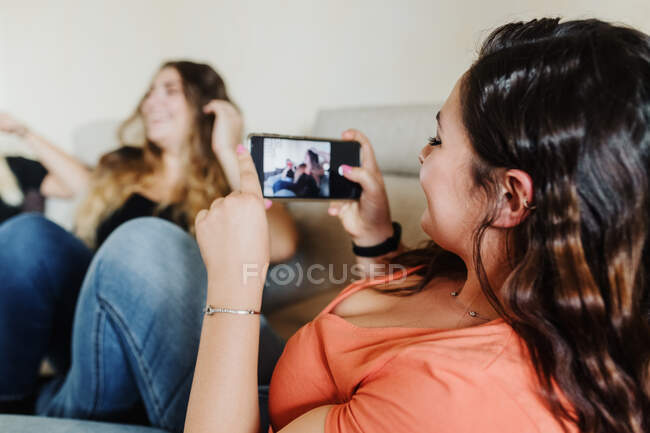 Jeune femme photographier des amis avec téléphone — Photo de stock