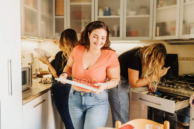 Amigos preparando comida juntos en la cocina - foto de stock