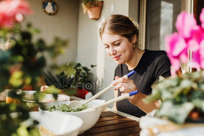 Mujer joven sirviendo ensalada - foto de stock