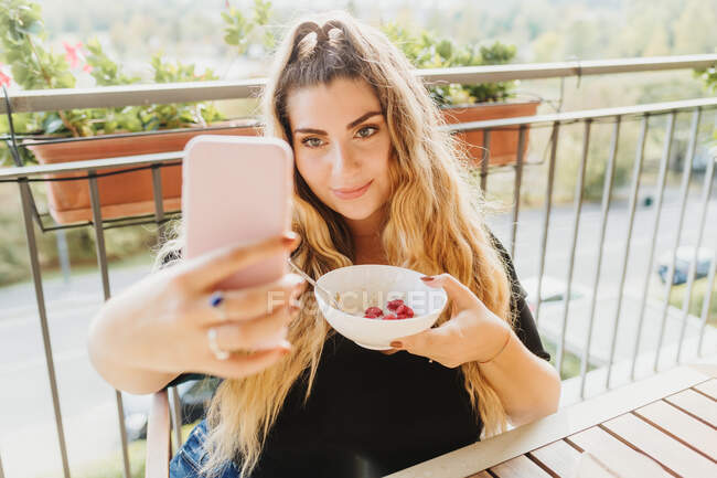 Giovane donna che prende selfie con ciotola sana colazione — Foto stock