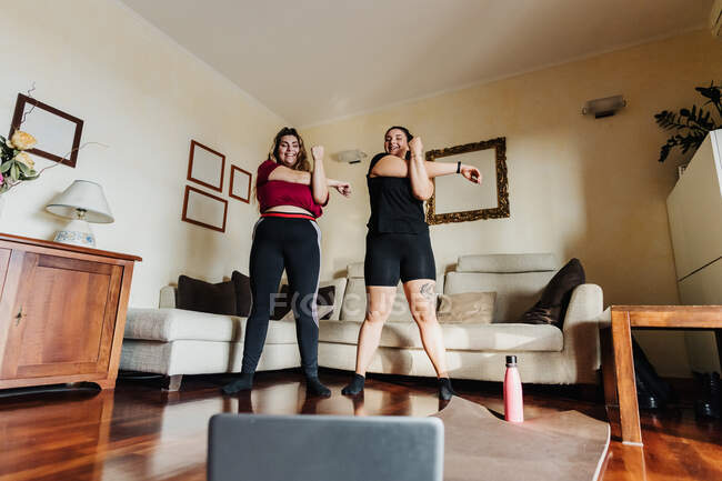 Dos mujeres tomando clases de ejercicio en línea juntas - foto de stock