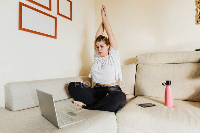 Молодая женщина растяжения, принимая онлайн класс упражнений — стоковое фото