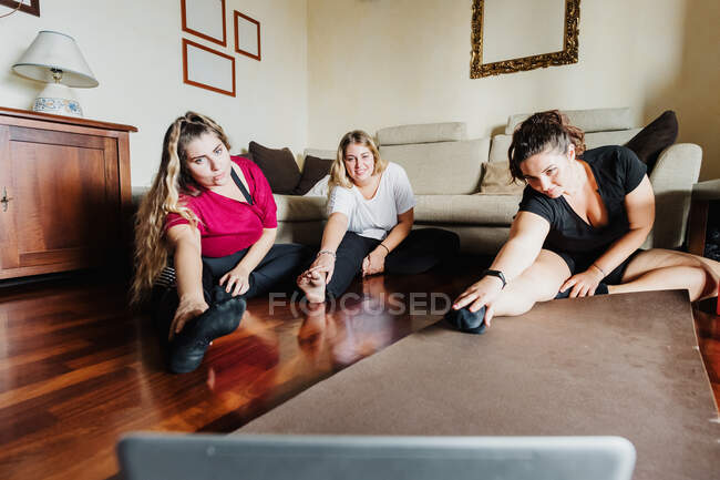 Друзья-женщины растягиваются, вместе ходят на занятия по онлайн-физкультуре — стоковое фото