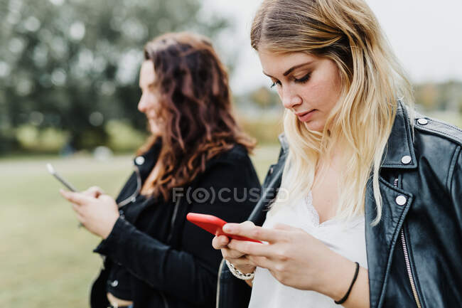 Dos mujeres jóvenes mirando sus teléfonos - foto de stock