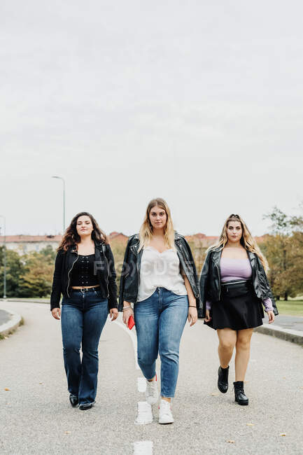 Trois jeunes femmes marchant sur la route — Photo de stock